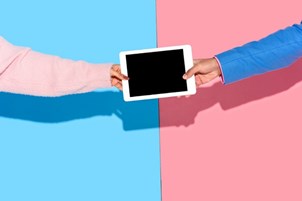 Two people holding tablet across a divide