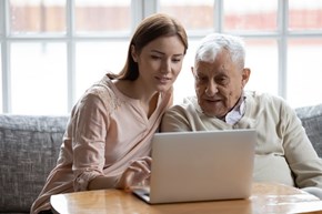 Young woman with old man at laptop