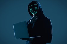Man in hoodie and mask with laptop